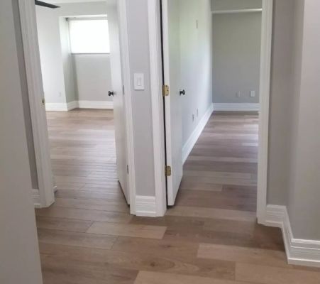 clean light oak flooring from a hallway leading toward 2 bedrooms in a rental unit